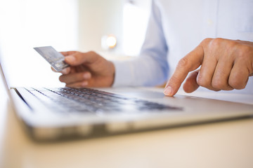 Fototapeta premium Man using credit card and laptop, shopping on line.indoor