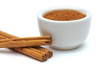 Schale mit gemahlenem Zimt neben Zimtstangen