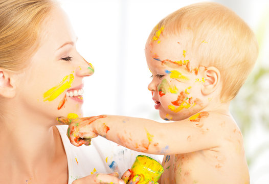 happy dirty baby draws paints on her face of mother