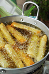 Spring rolls, fried in a pan.
