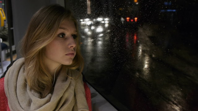 beautiful girl on a tram at night looking out the window