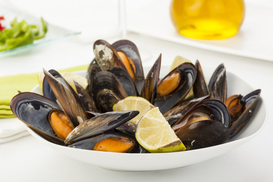 plate of coocked mussels with lemon isolated over white