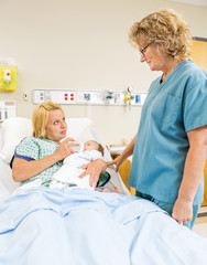 Female Nurse Looking At Patient Feeding Milk To Babygirl
