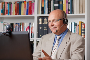 Elderly man with headphone and computer smiling