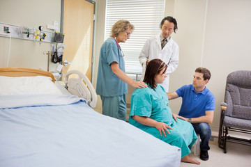 Obraz premium Medical Team And Man Looking At Pregnant Woman In Hospital