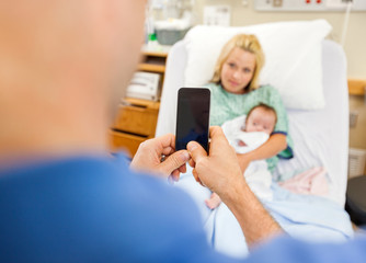 Man Photographing Woman And Babygirl Through Cell Phone