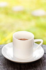 White cup of coffee on table with landscape background