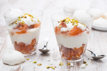 dessert with canned peaches, whipped cream and meringue in glass