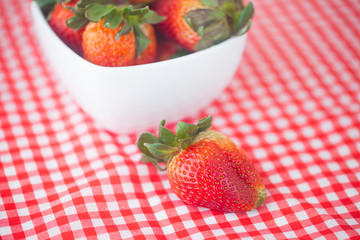 strawberries in bowl on checkered fabric