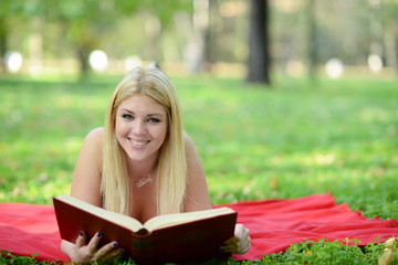 Fototapeta na wymiar Happy smiling woman reading book in park