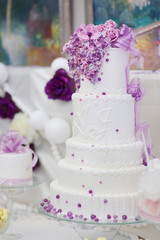 Fototapeta na wymiar Biały tort weselny ozdobiony fioletowymi kwiatami