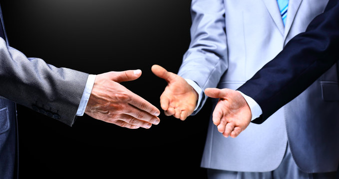 Two business men shaking hands to their leader, close up