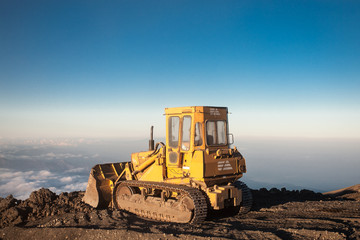 Yellow tractor at the top of the Etna mountain with view on the