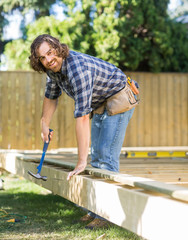 Manual Worker Hammering Nail Into Wood At Site