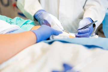 Doctor Stitching Patient's Wound While Nurse Assisting Him