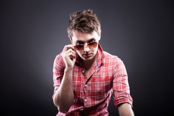 Handsome young man with sunglasses on dark background