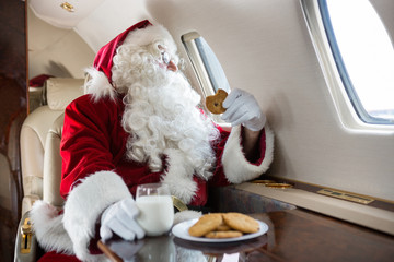 Santa Holding Cookie While Looking Through Private Jet's Window