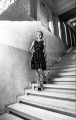 elegant woman in short dress walking down marble stairs