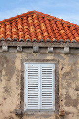 Building with orange roof tiles and wodden shuttered window