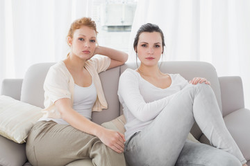 Fototapeta na wymiar Two serious female friends sitting on sofa in the living room