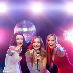 three smiling women dancing and singing karaoke