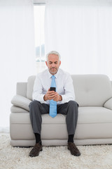 Elegant mature businessman text messaging at home