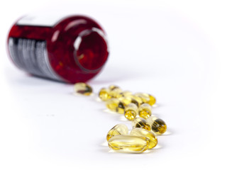 Fish oil capsules from a red jar over a white background