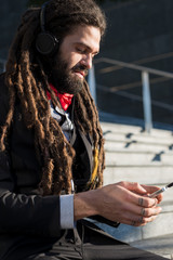 Stylish elegant dreadlocks businessman listening music
