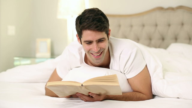 Smiling handsome man reading in bed