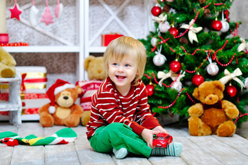 Cheerful little boy playing with his red toy car