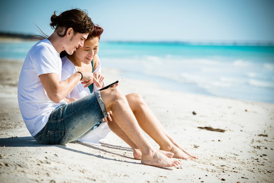 Couple togetherness surfing with tablet on the beach