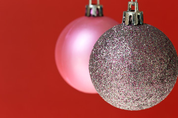 Two different Christmas ornaments on red background.	