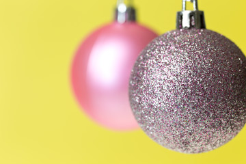 Two different Christmas ornaments on yellow background.	