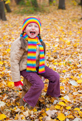 girl in autumn park sit on stump and show tongue