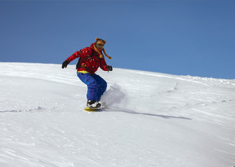 Snowboarder doing a toe side carve with deep blue sky in backgro