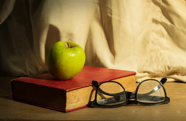 Antique book with eyeglasses and green apple
