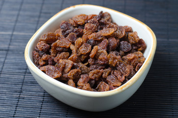 Bowl of raisins on dark background