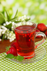 Delicious strawberry tea on table on bright background
