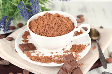 Cocoa powder in cup on napkin on wooden table