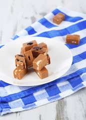 Many toffee on plate on napkin on wooden table