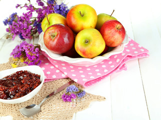 Juicy apples on plate on white wooden table
