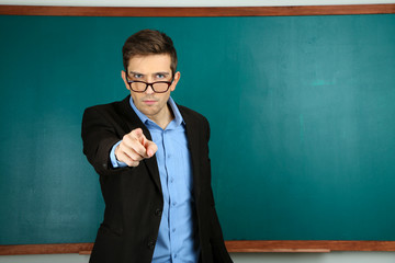 Young teacher near chalkboard in school classroom