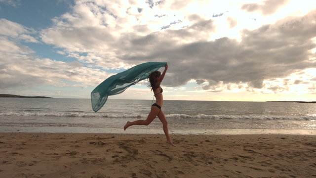 Woman running at the beach holding a scarf