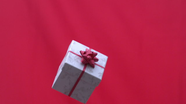 Christmas present tossed into the air on red background