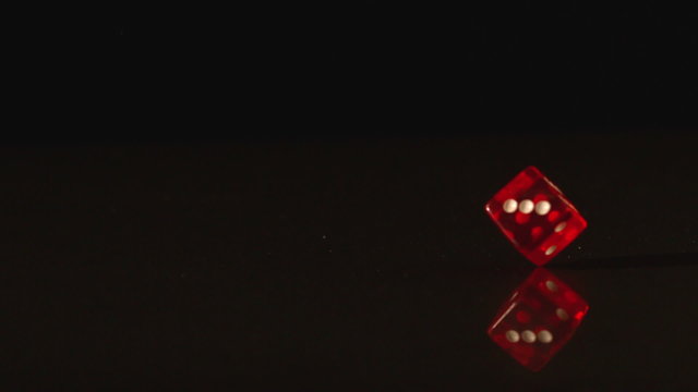 Red plastic dice revolving on black background
