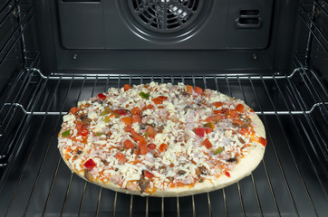 Raw and frozen pizza in the oven.