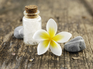 frangipani flower with salt in glass and stones on driftwood