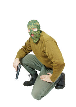 Man wearing camouflage mask with a pistol