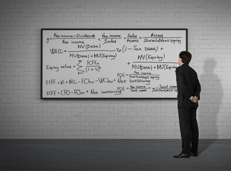 Obraz premium Businessman with formulas (brick background)