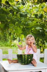 blonde litle girl eats a slice of watermelon
